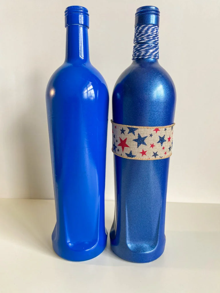 2 blue bottles, one with glossy primer and one with shimmer topcoat, burlap ribbon with red and blue stars, blue and white bakers twine on neck