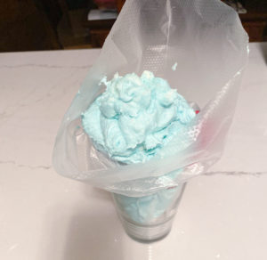 Decorating bag in a drinking glass, filled with blue buttercream icing