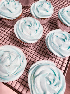 Cupcakes with blue icing roses on a cooling rack