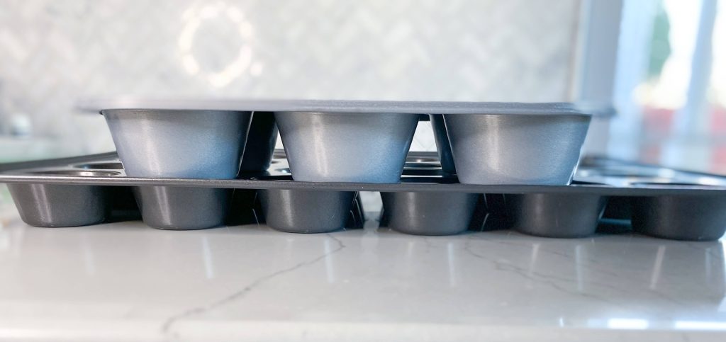 side view of jumbo cupcake pan on top of standard cupcake pan. Jumbo pan is twice as deep as standard pan.