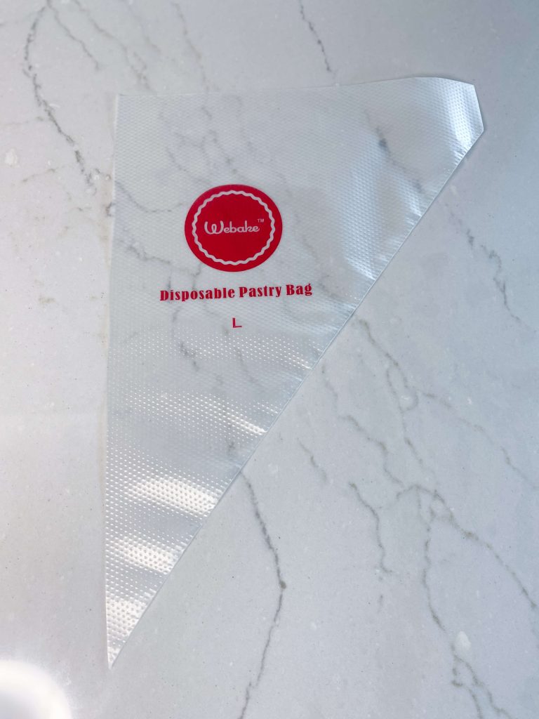 Clear plastic pastry bag, triangle shaped with red Webake logo and Disposable Pastry Bag L, textured raised dots on exterior
