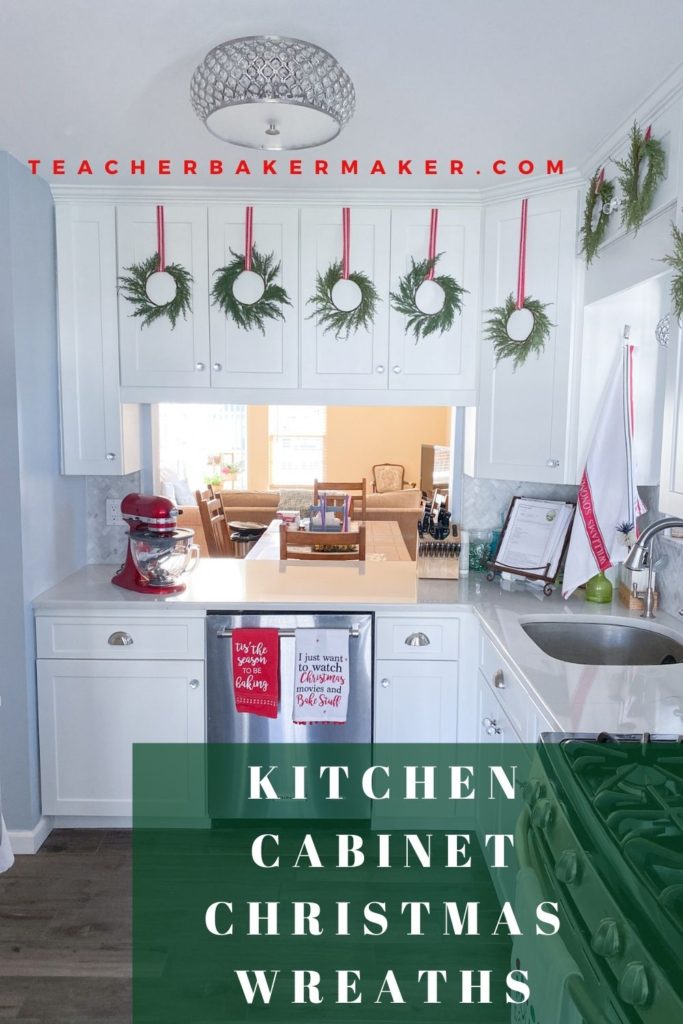 Pin Image of white kitchen cabinets with green wreaths hung on upper cabinets with red and white ribbon with text overlay of Kitchen Cabinet Christmas Wreaths