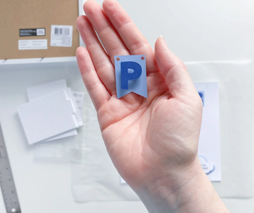 Dark blue letter "P" mounted with foam adhesive square onto light blue cardstock pennant
