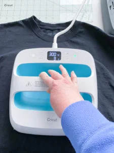 Cricut Easy Press set to 300 degrees with 9 seconds left, on top of black t-shirt