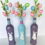 Easter Decorations Ideas spray painted glass bottles two multicolor glitter purple one gloss blue with bunny decals with cotton ball tails pastel twine Easter egg sprays