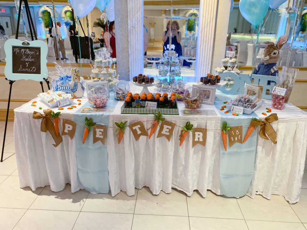 Peter Rabbit-themed sweets table with cupcake stands, candy, and chocolate covered strawberries