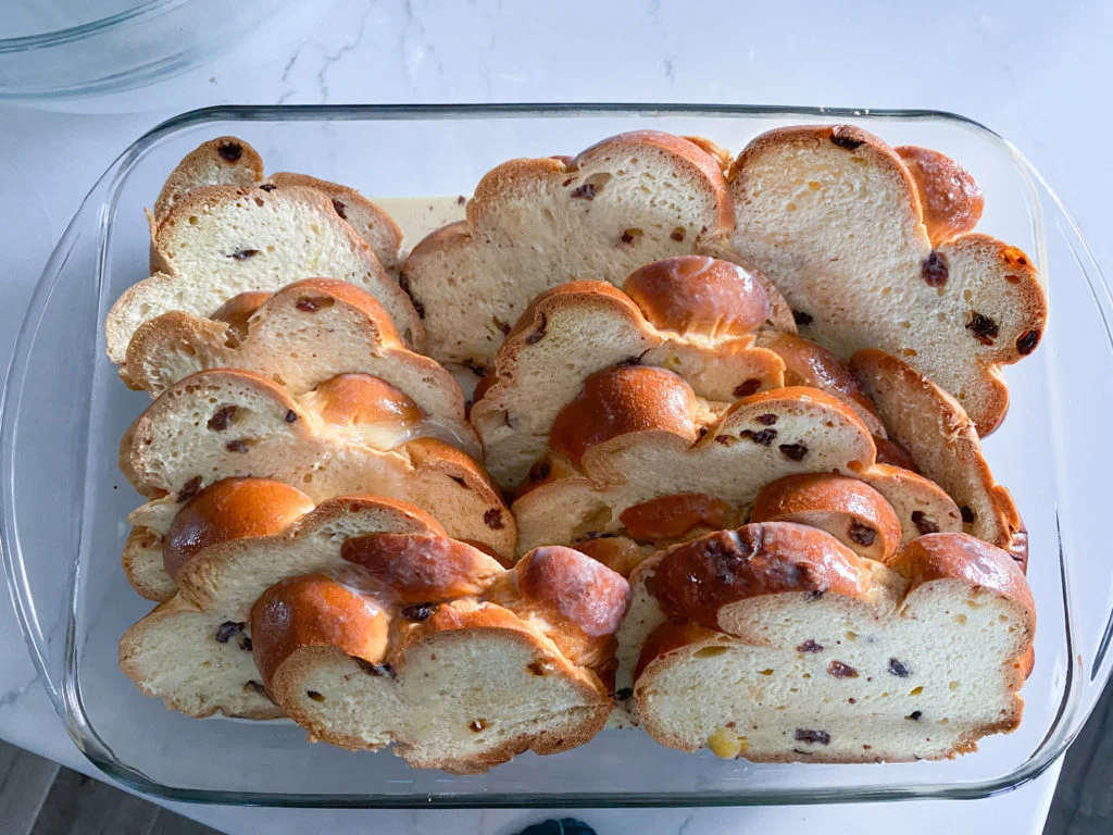 raisin challah slices shingled in casserole dish with batter