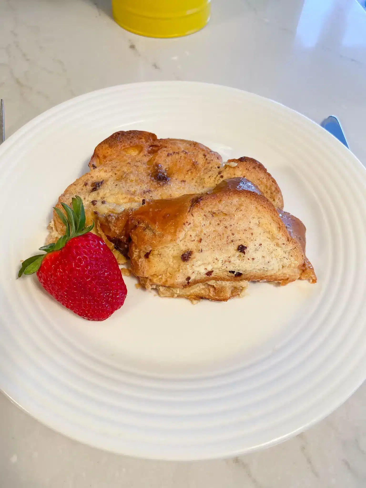 2 slices raisin challah french toast with strawberry on white plate