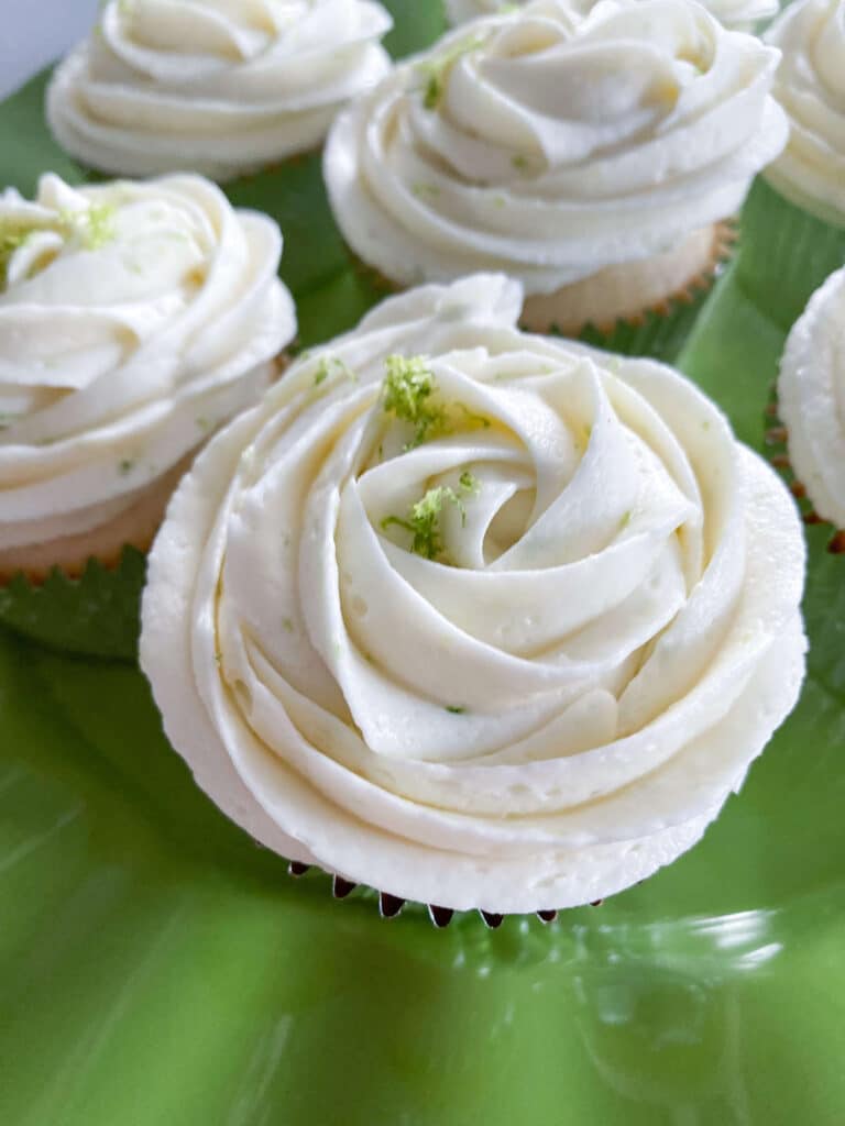 lime green plate with lime coconut cupcakes decorated with white lime buttercream and lime zest