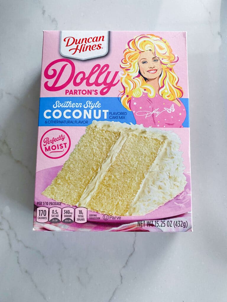 front of package of Duncan Hines Dolly Parton Coconut cake mix showing slice of cake with white frosting and cartoon image of Dolly Parton
