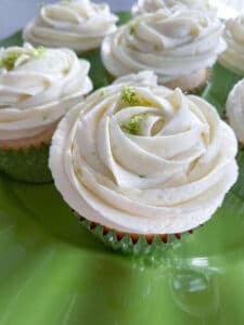lime coconut cupcakes on lime green platter with buttercream rose frosting and lime zest