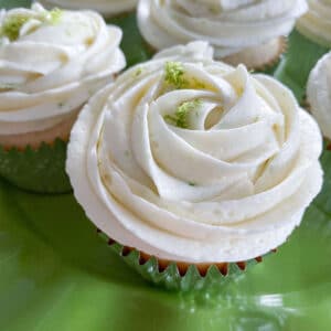 lime coconut cupcakes on lime green platter with buttercream rose frosting and lime zest