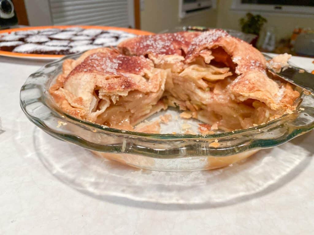apple pie with 2 slices removed, in glass pie pan