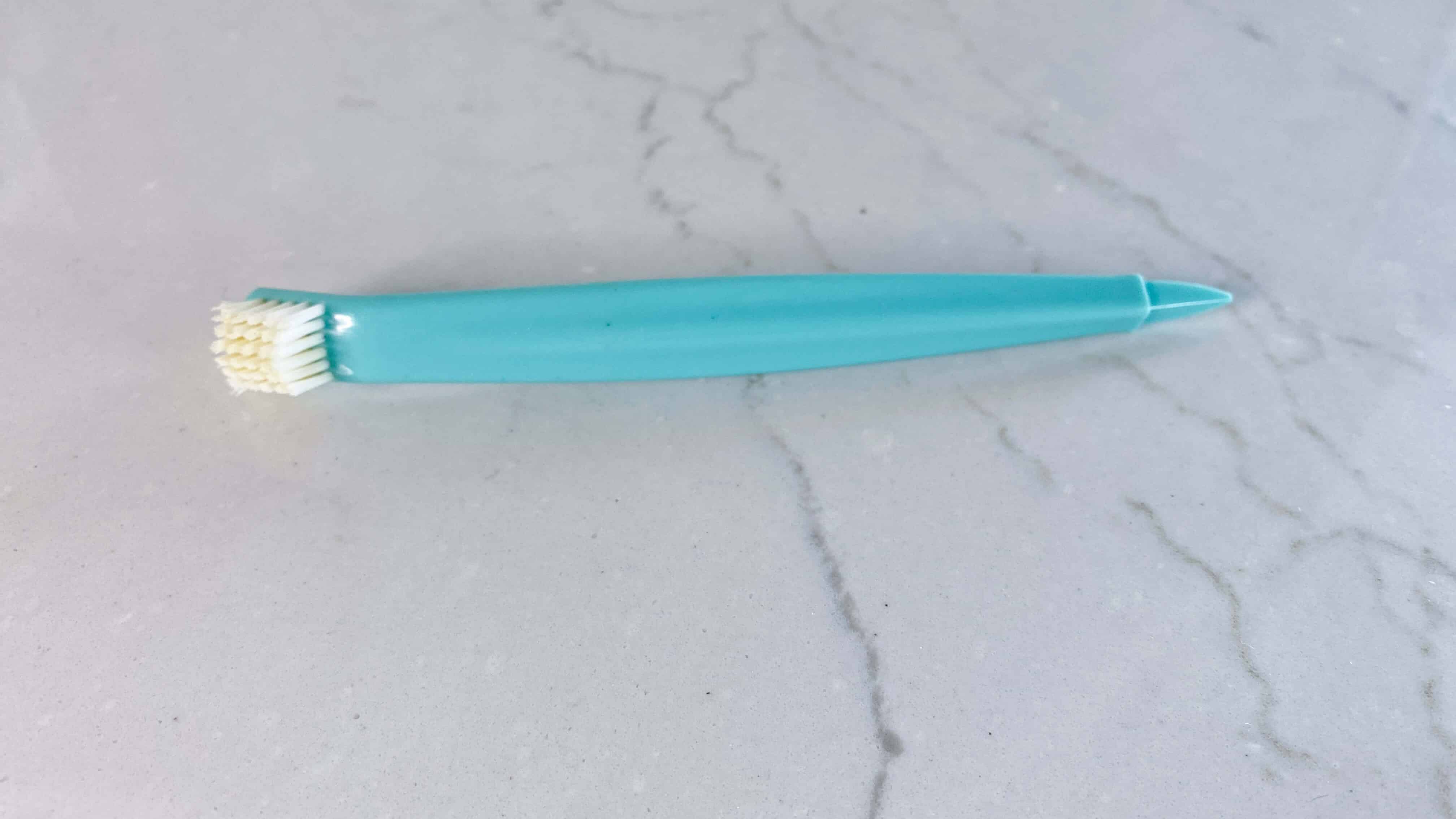 turquoise Bundt pan cleaning tool with dual brush on one end and point on other end
