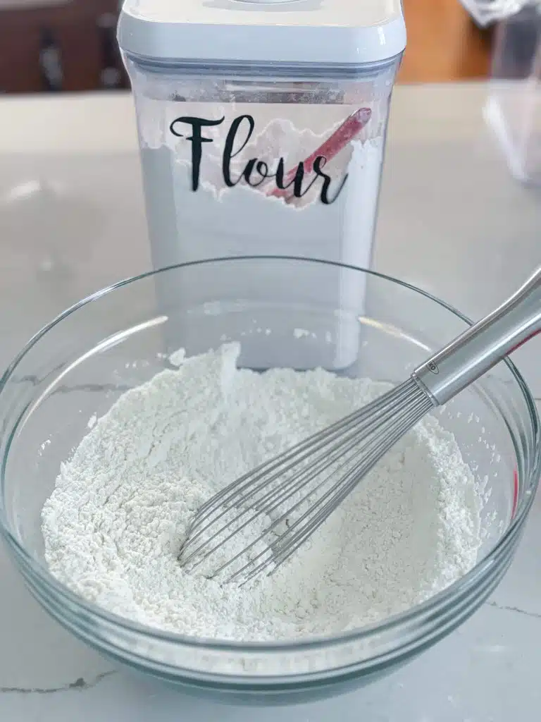 bowl of flour and salt with whisk in front of flour canister