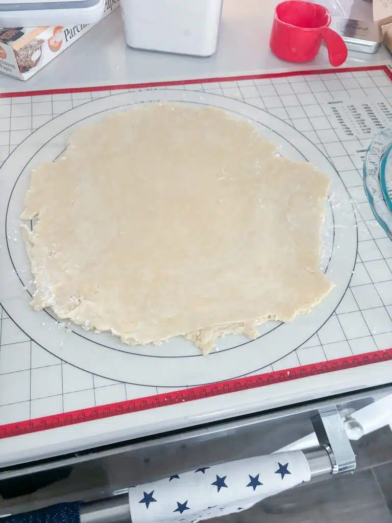 Pie crust rolled out on marked pastry mat into a circle