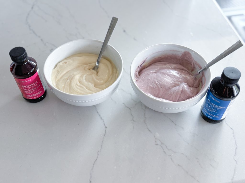 bowls of white and blue batter next to bottles of raspberry and blueberry emulsions