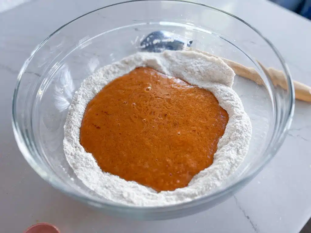 bowl of dry ingredients with wet pumpkin puree mixture poured in well in center