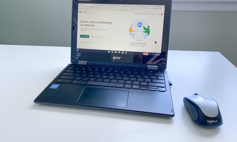 Chromebook and wireless mouse on white table, open to Google Meet