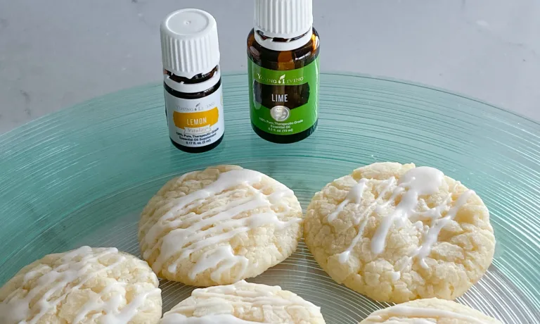 Glazed Lemon Lime cookies on blue green glass plate with bottles of Young Living brand lemon and lime essential oils