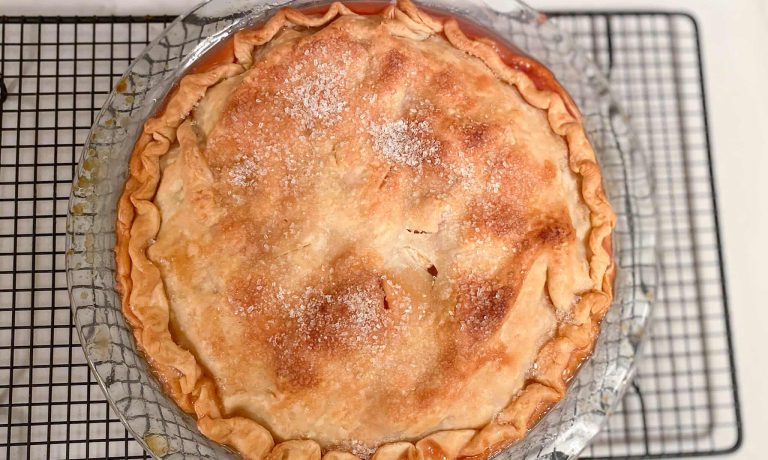 freezer apple pie baked in glass pie pan cooling on cooling rack